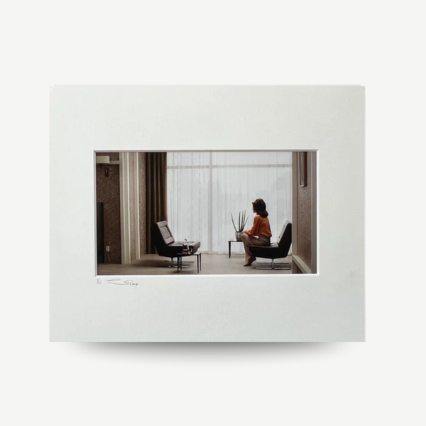 Framed photograph of a woman sitting in a modern room with large windows. Erwin Olaf - Caroline from the 'Grief' series