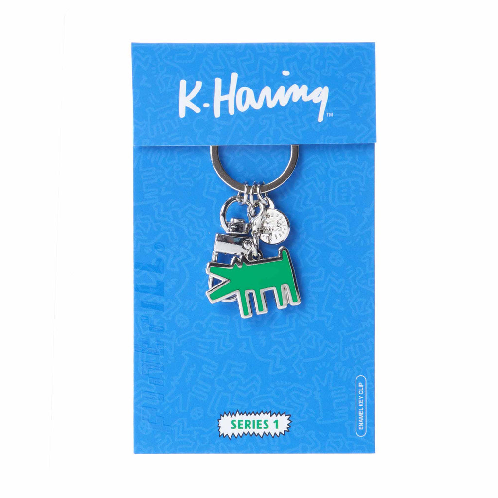 Keychain with green and silver design on a blue K. Haring branded card