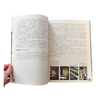 Open book with text and images held by a hand on a white background