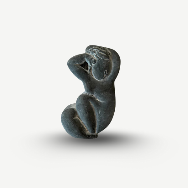 Black stone sculpture of a seated figure on a white background Amedeo Modigliani - Cariatide